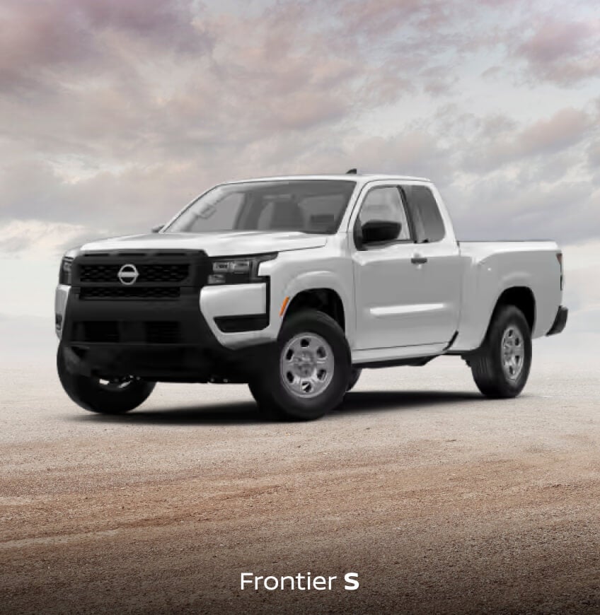 Front three-quarter view of a white Nissan Frontier S on dirt ground under a cloudy sky.