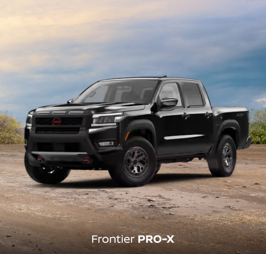 Front three-quarter view of a black Nissan Frontier PRO-X on dirt ground under a cloudy sky.
